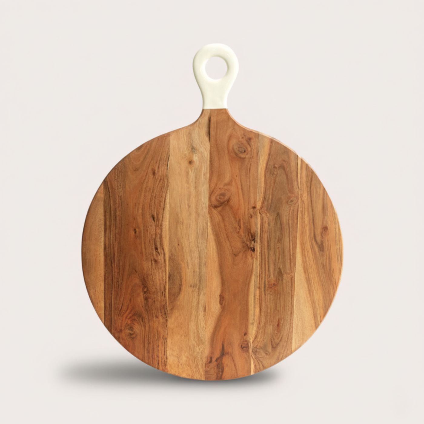 Round wooden cutting board with a white handle on a light beige background