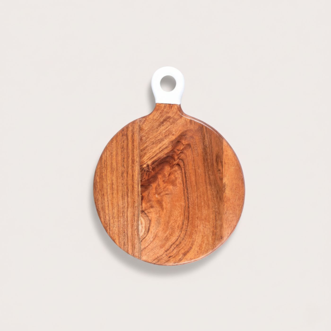 Wooden round cutting board with a white handle on a light gray background