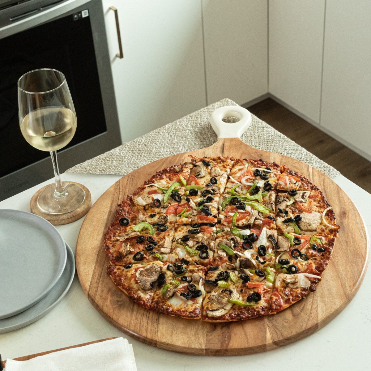 Pizza Peel Shaped Round Pizza Paddle Charcuterie Board with White Enamel Handles image with pizza and wine lifestyle image - Aesthetic Living