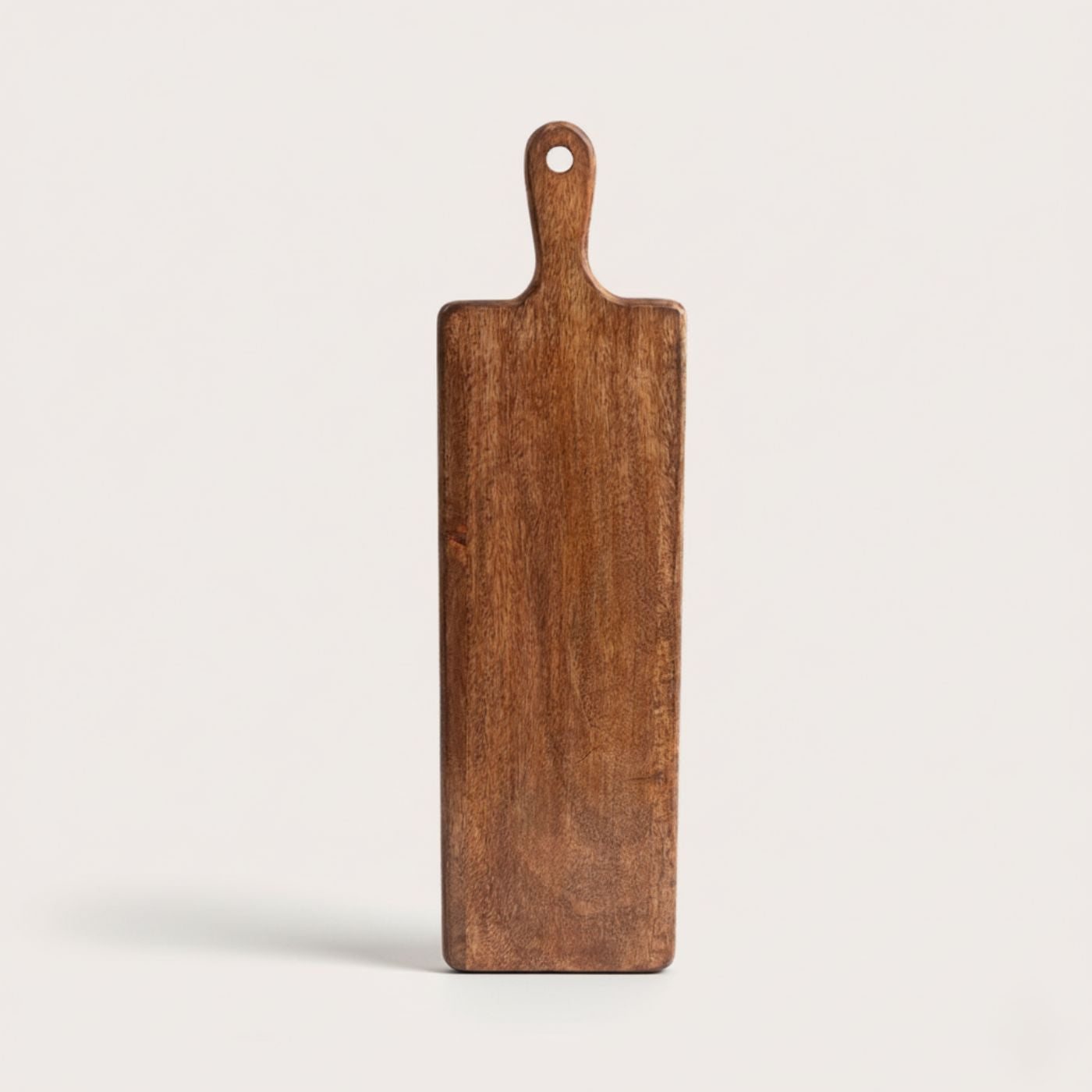 Long wooden cutting board with a handle on a light gray background