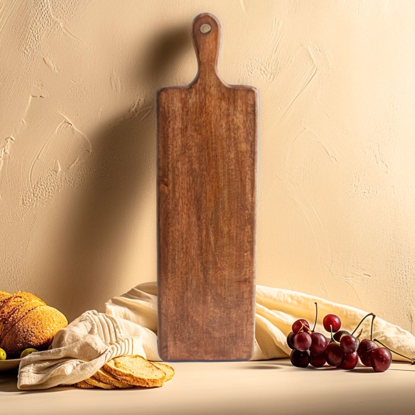 Wooden cutting board leaning against a beige wall with fruits on a table below.